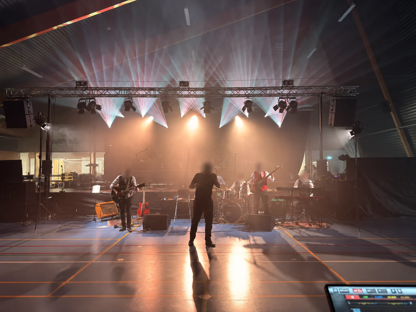 A band at Hovedgaard byfest under white beams and warm amber lighting.